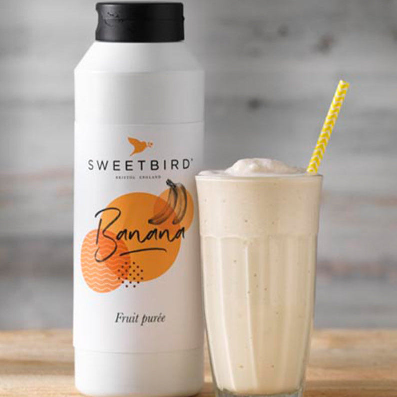 Sweetbird banana fruit juice bottle with a glass of banana smoothie on a wooden surface.