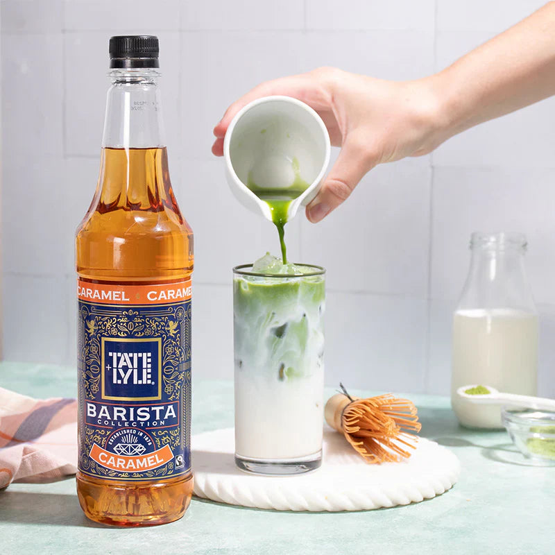 Tate & Lyle Barista Collection Caramel syrup being poured into a glass with ice and green liquid.